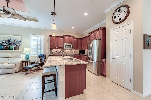 kitchen featuring tasteful backsplash, pendant lighting, a kitchen bar, sink, and appliances with stainless steel finishes