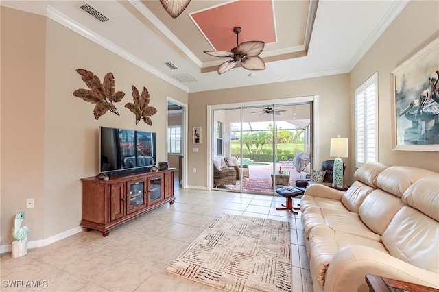 tiled living room featuring ceiling fan, a tray ceiling, and ornamental molding