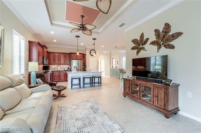 living room featuring ceiling fan, light tile patterned floors, crown molding, and a tray ceiling