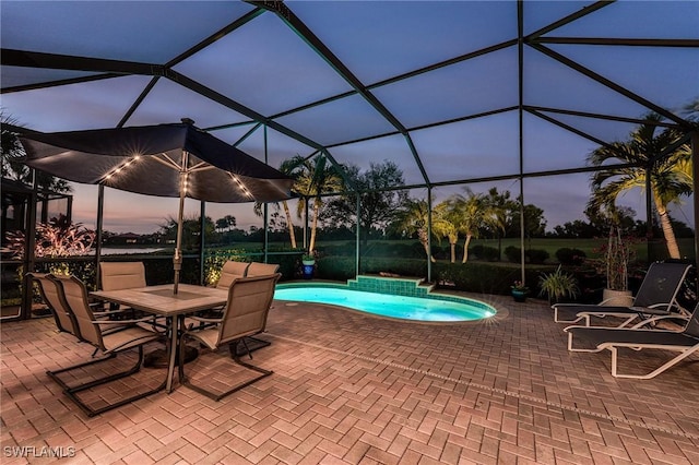 pool at dusk with a patio area and glass enclosure