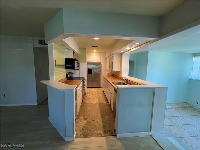 kitchen with white cabinetry, sink, black range with electric cooktop, stainless steel fridge with ice dispenser, and kitchen peninsula