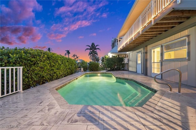 pool at dusk with a patio area