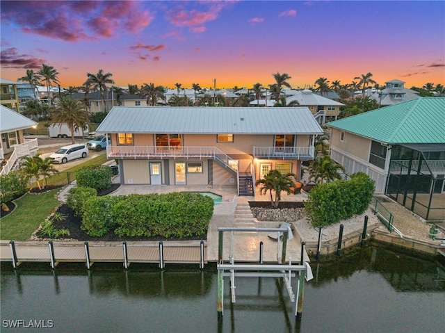 back house at dusk featuring a balcony and a water view