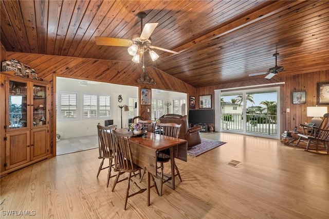 dining room featuring a wealth of natural light, lofted ceiling, and wooden walls