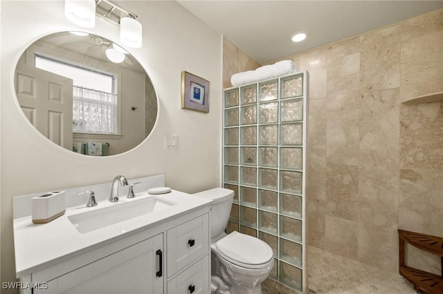 bathroom with tiled shower, vanity, and toilet