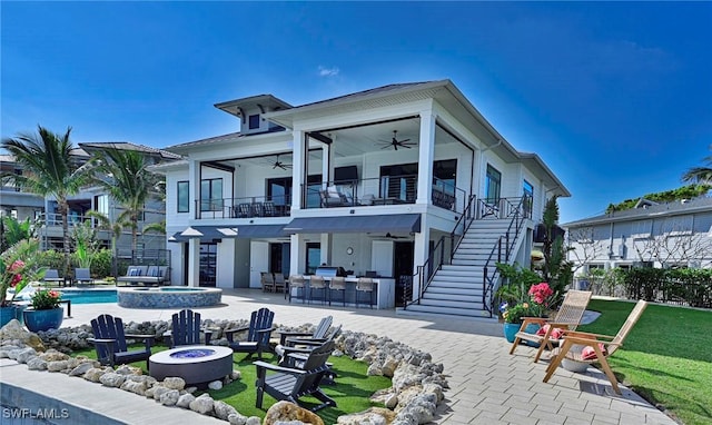 back of property featuring ceiling fan, an outdoor fire pit, an outdoor bar, a balcony, and a patio