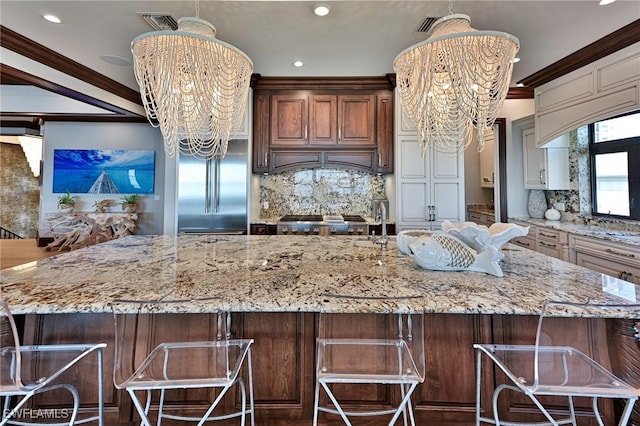 kitchen with decorative backsplash, light stone counters, and a notable chandelier