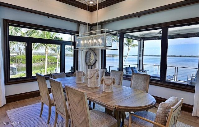 dining room with crown molding, plenty of natural light, a water view, and wood-type flooring