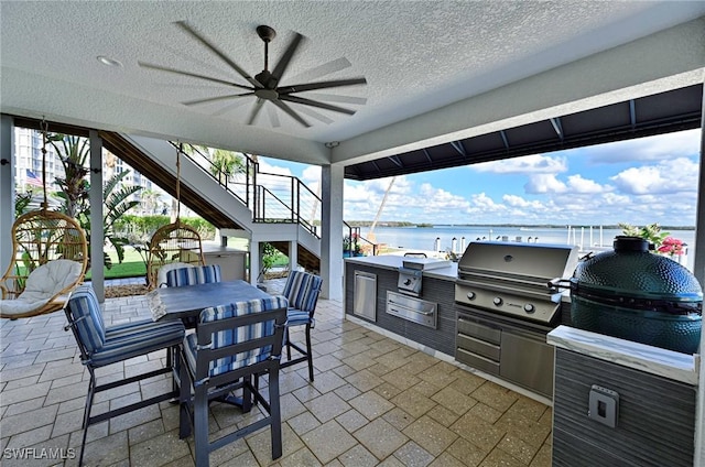 view of patio featuring an outdoor kitchen, a water view, area for grilling, and ceiling fan