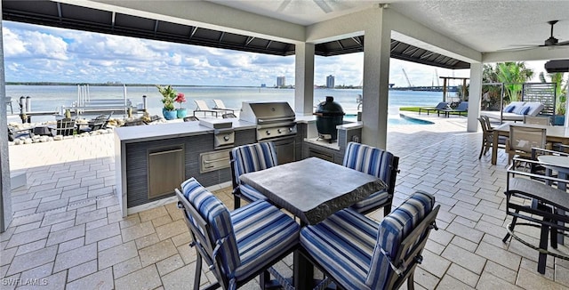 view of patio with area for grilling, ceiling fan, and a water view