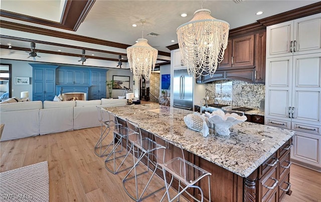 kitchen with pendant lighting, white cabinets, a kitchen breakfast bar, ceiling fan with notable chandelier, and decorative backsplash