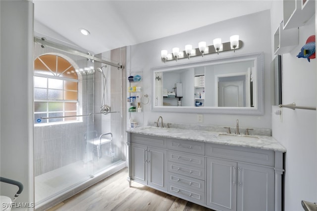 bathroom with hardwood / wood-style floors, vanity, lofted ceiling, and walk in shower