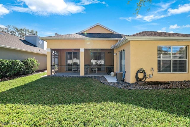 rear view of house featuring a yard, a patio area, and a sunroom