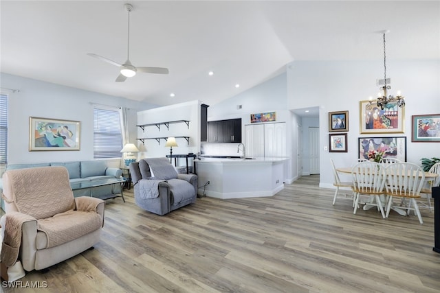 living room with ceiling fan with notable chandelier, sink, high vaulted ceiling, and light hardwood / wood-style flooring