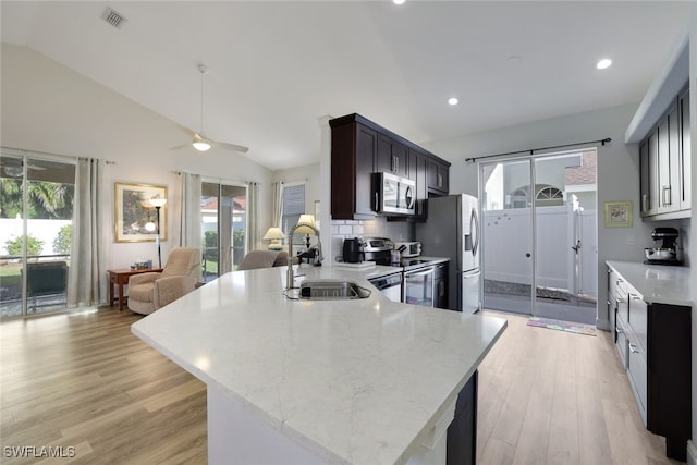 kitchen with sink, a healthy amount of sunlight, lofted ceiling, and appliances with stainless steel finishes