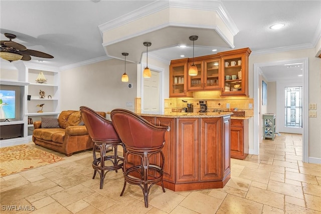 bar with decorative light fixtures, ceiling fan, light stone countertops, and ornamental molding