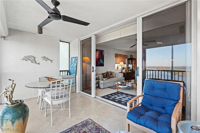 interior space with light tile patterned floors, a textured ceiling, a ceiling fan, and a textured wall