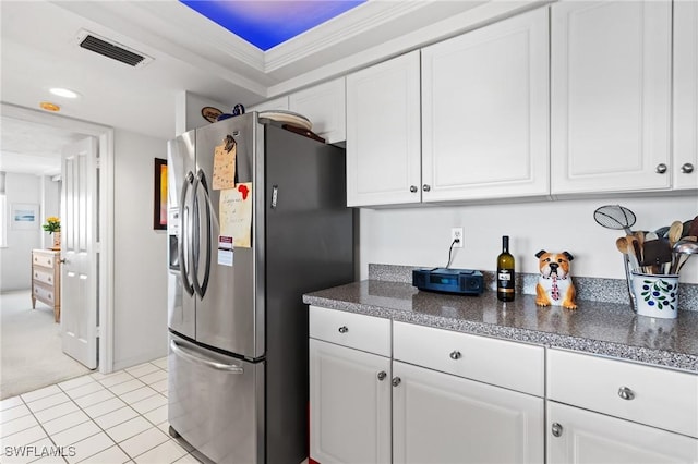 kitchen with dark countertops, white cabinetry, and stainless steel fridge with ice dispenser