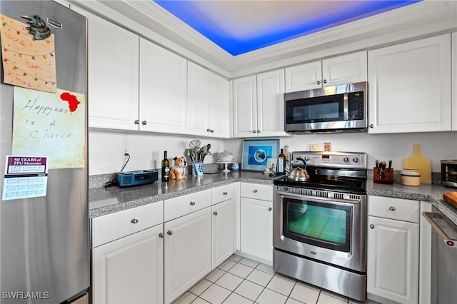 kitchen with stainless steel appliances, dark countertops, white cabinetry, and light tile patterned flooring