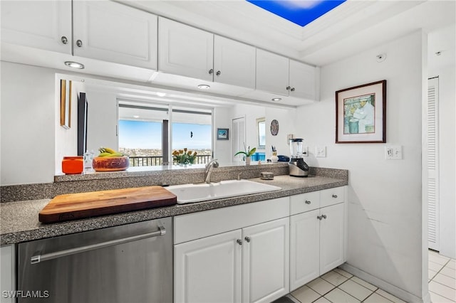 kitchen featuring light tile patterned floors, a sink, white cabinets, dishwasher, and dark countertops