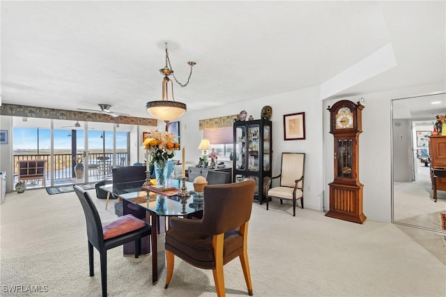 dining space featuring a ceiling fan and light carpet