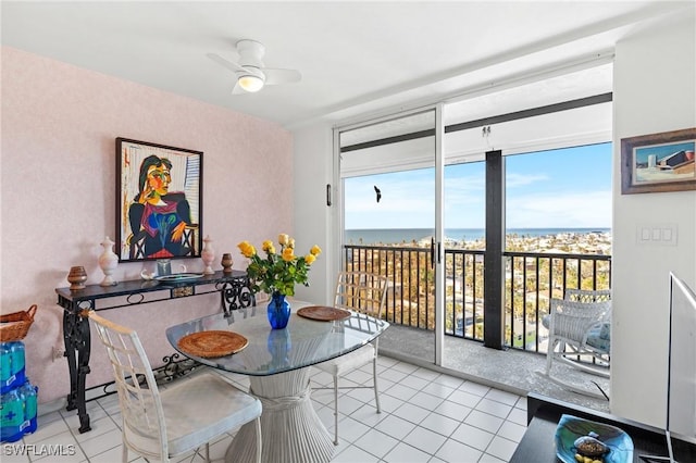 dining room featuring expansive windows, ceiling fan, light tile patterned floors, and a water view