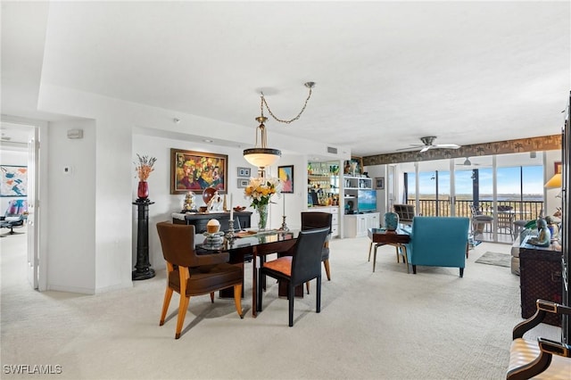 dining space with a ceiling fan and light colored carpet