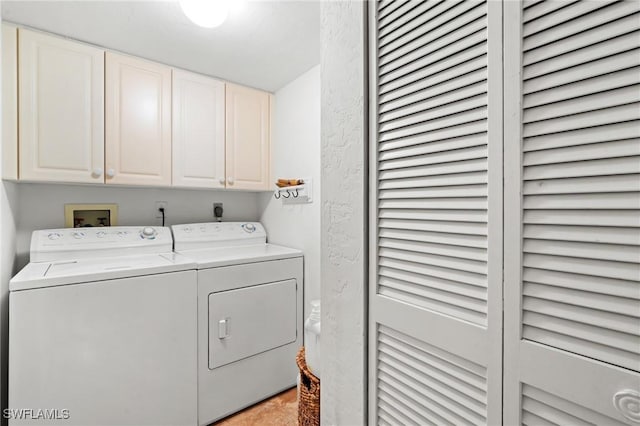 laundry area featuring washer and dryer, cabinet space, and a textured wall