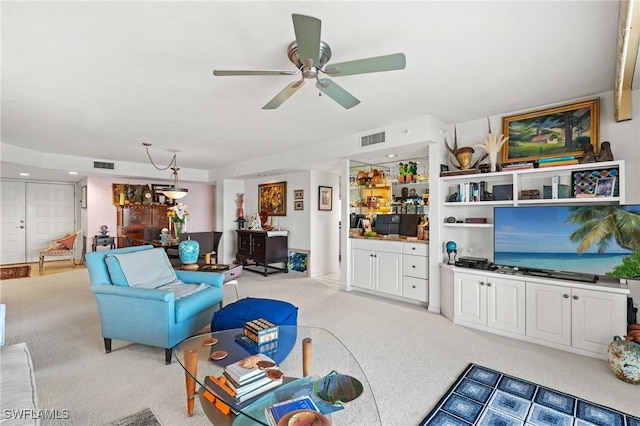 living area with visible vents, a ceiling fan, and light colored carpet