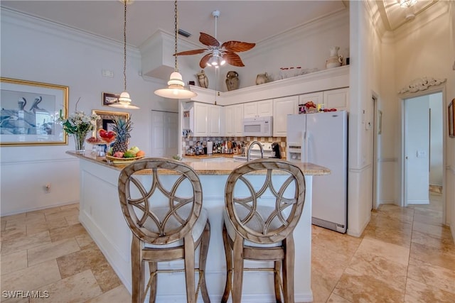 kitchen featuring light stone countertops, white cabinetry, crown molding, decorative light fixtures, and white appliances