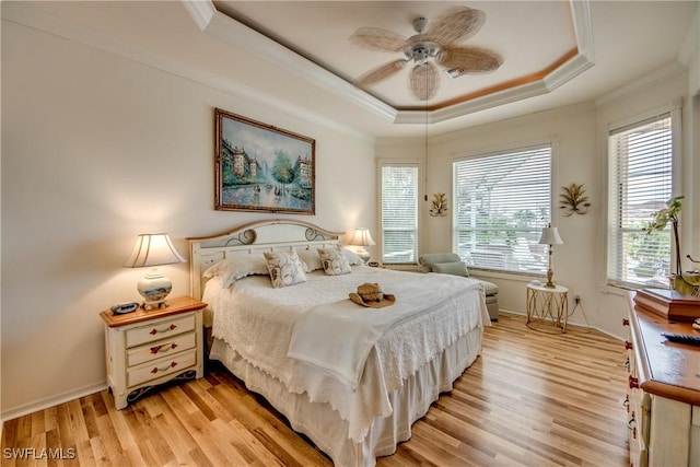 bedroom with multiple windows, light hardwood / wood-style floors, a raised ceiling, and ceiling fan