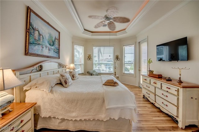 bedroom featuring a tray ceiling, light hardwood / wood-style flooring, ceiling fan, and crown molding