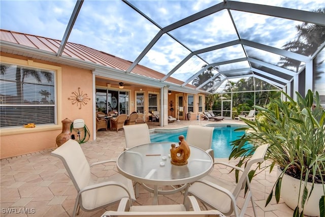 view of pool with glass enclosure, ceiling fan, a patio area, and an outdoor hangout area