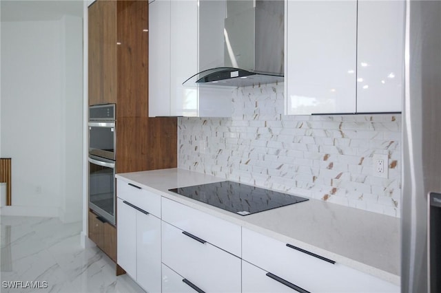 kitchen featuring backsplash, wall chimney exhaust hood, black electric cooktop, double oven, and white cabinetry