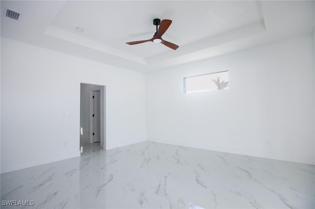 unfurnished room with ceiling fan and a raised ceiling