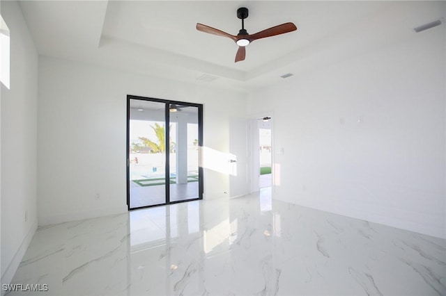 empty room featuring a tray ceiling and ceiling fan