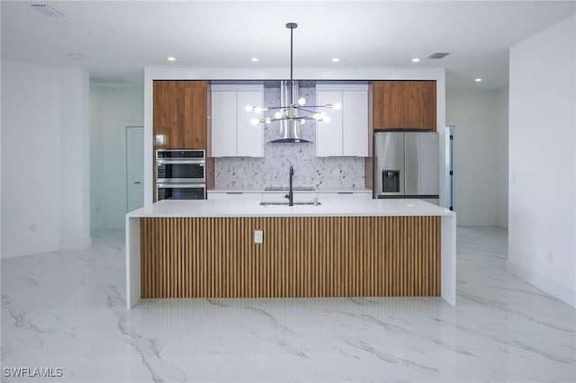 kitchen featuring pendant lighting, stainless steel appliances, white cabinetry, and a center island with sink