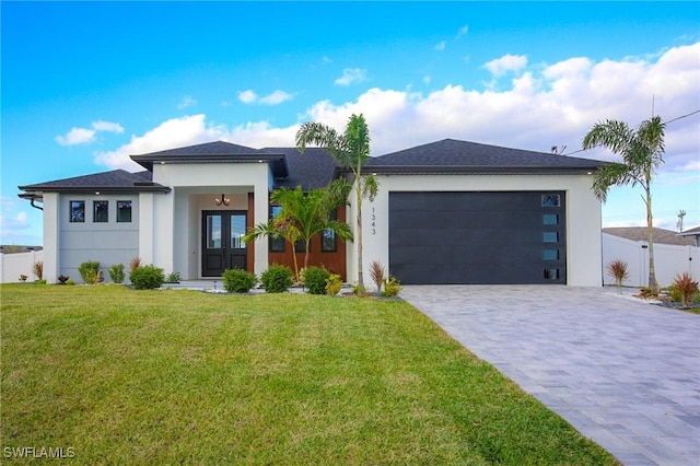 prairie-style home with a garage, a front yard, and french doors