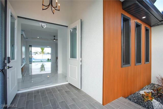 foyer with ceiling fan with notable chandelier