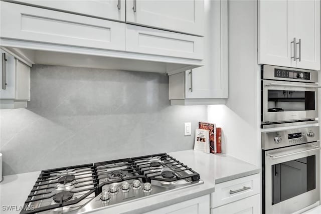 kitchen featuring decorative backsplash, appliances with stainless steel finishes, and white cabinetry