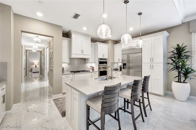 kitchen with appliances with stainless steel finishes, a center island with sink, pendant lighting, and sink