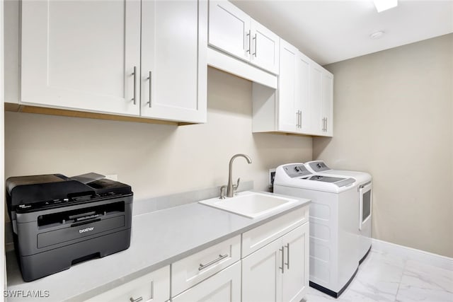 washroom with cabinets, washing machine and dryer, and sink