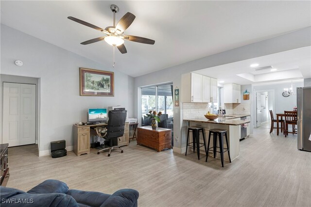 office area featuring ceiling fan with notable chandelier, light wood-type flooring, lofted ceiling, and sink