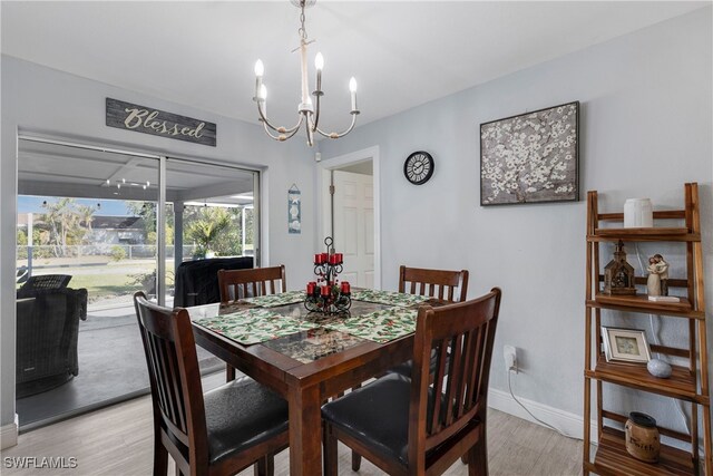 dining room featuring light wood-style floors, a chandelier, and baseboards