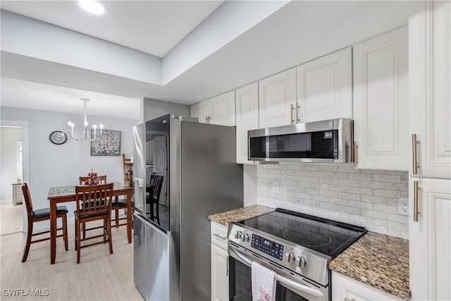 kitchen with appliances with stainless steel finishes, tasteful backsplash, white cabinetry, and dark stone counters