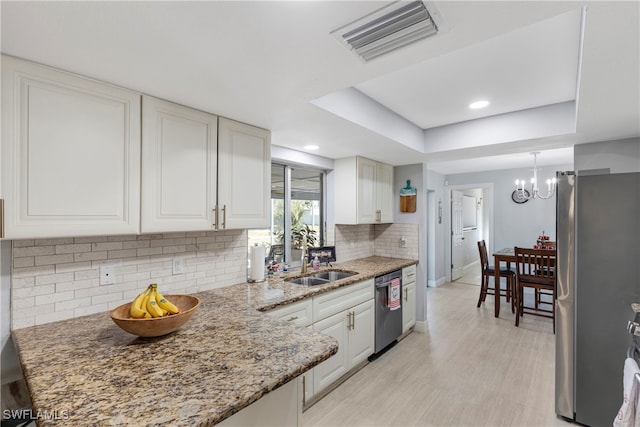 kitchen featuring white cabinets, sink, light hardwood / wood-style flooring, tasteful backsplash, and stainless steel appliances