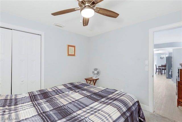 bedroom featuring a closet, light colored carpet, visible vents, baseboards, and ceiling fan with notable chandelier