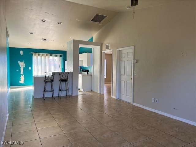 kitchen featuring a kitchen bar, light tile patterned floors, high vaulted ceiling, and ceiling fan