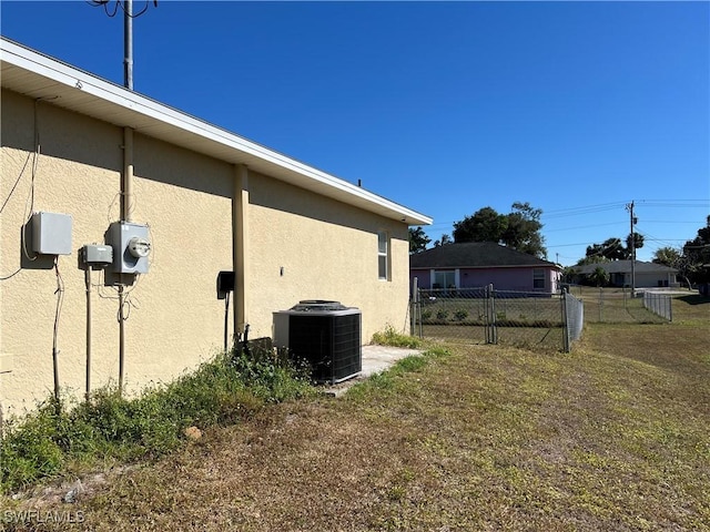 view of side of home featuring central AC and a lawn