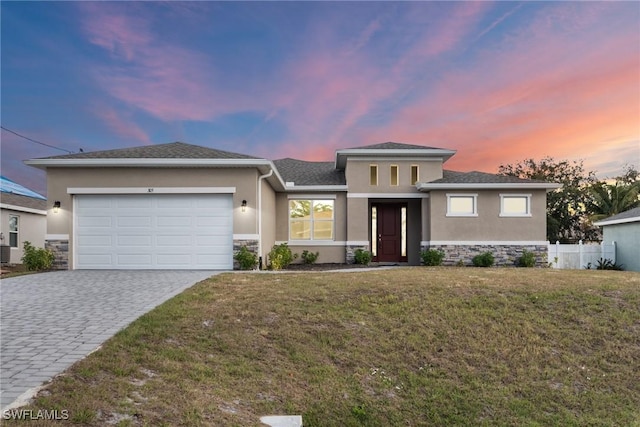 prairie-style home featuring a garage and a lawn